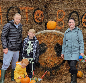 Image shows a family posing with their haul from the pumpkin patch at Lower Drayton Farm